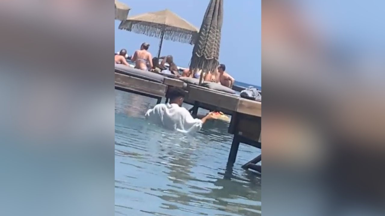 Plajda çalışan garsonların sipariş götürmek için suya girmesine tepki
